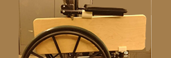 Wheelchair with transfer board stowed between the wheel and the arm rest.